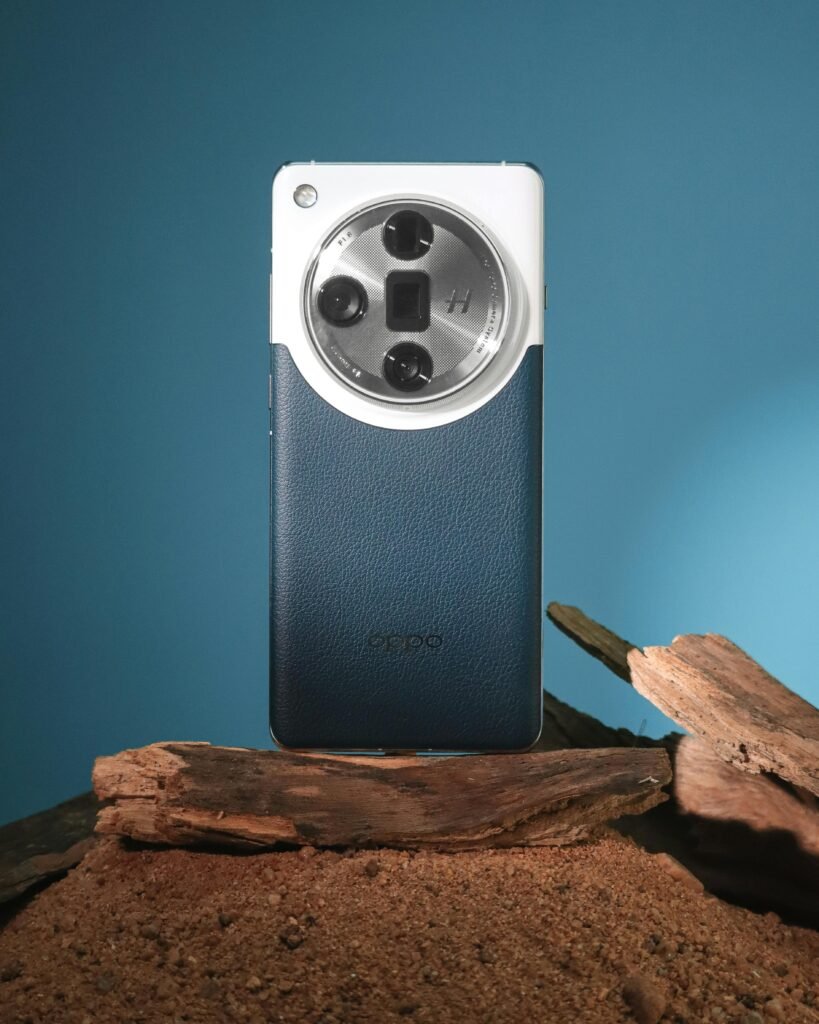 pexels-photo-20895985-20895985 Close-up shot of a stylish smartphone with circular camera design on wood against blue background.